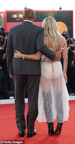 كان كيفن يبدو أنيقًا في بدلة رمادية وقميص أبيض ناصع، بينما كان يخفي عينيه خلف النظارات الشمسية