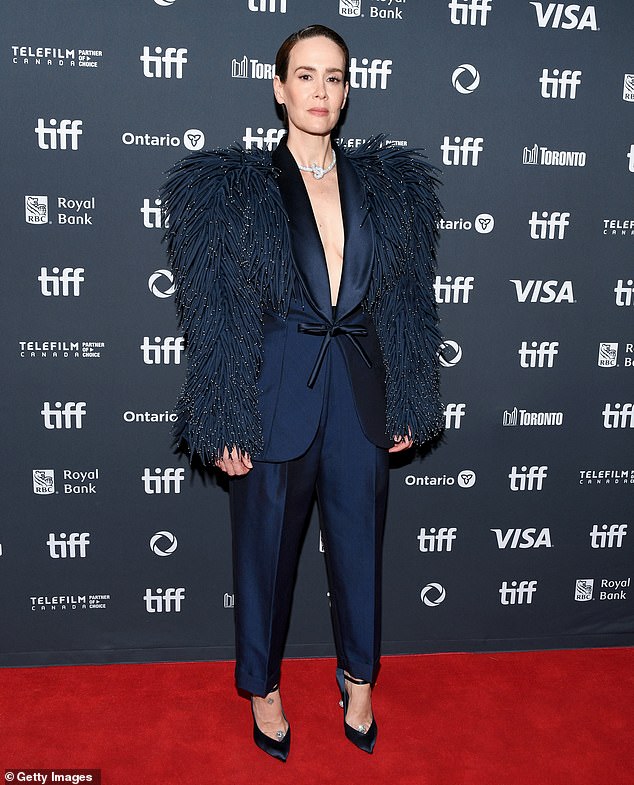 كشفت عن فتحة صدرها الناعمة، وكان سترتها الأنيقة ذات أكمام درامية تشبه الثعبان مما منحها مظهرًا ظليًا قويًا