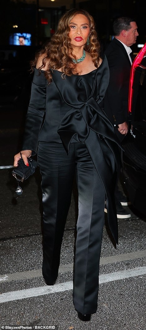 صممت تينا زيًا أنيقًا من الساتان الأسود يتميز بجزء علوي مثير بدون أكتاف مع فيونكة كبيرة في المقدمة