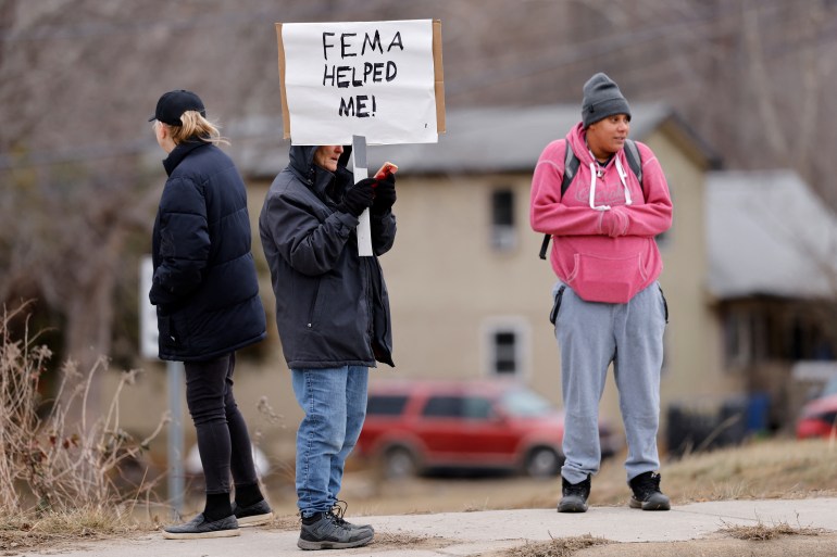 الشخص يحمل علامة في ولاية كارولينا الشمالية تقرأ "ساعدني FEMA"