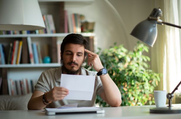 رجل أعمال مضغوط غاضب يفتح مغلف قراءة الأخبار السيئة في رسالة