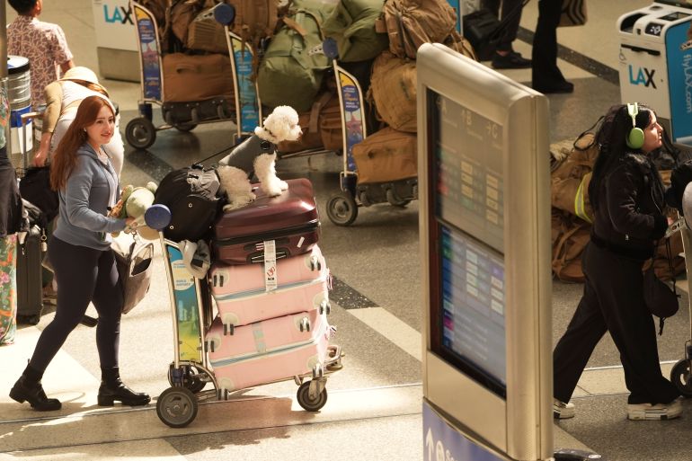 يدفع المسافرون عربات الأمتعة من خلال LAX.