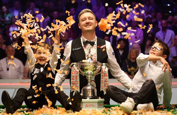 يطرح Kyren Wilson of England مع أطفاله على الطاولة بينما يرمي المرء حلويات إلى جانب كأس Cazoo World Snooker Championship بعد فوزه في المباراة النهائية بين Jak Jones of Wales و Kyren Wilson of England في اليوم السابع عشر من بطولة Cazoo World Snooker 2024 في مسرح Cruible في مايو 06 ، 2024 في Sheffiffield ،