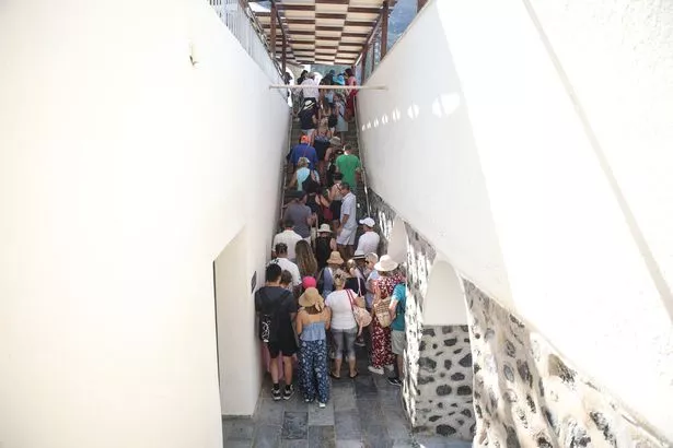 يصطفون السياح أثناء انتظارهم للحصول على الكابل من ميناء فيرا القديم إلى قرية فيرا في جزيرة سانتوريني اليونانية في 20 يوليو 2024. مثل الوجهات السياحية الشهيرة الأخرى ، تقترب جزيرة سيكلاديك التي تطفو على البركان على الإفراط في التشبع ، وتريد الآن تقييد سفن الرحلات البحرية. (تصوير Aris Oikonomou / AFP) (تصوير Aris Oikonomou / AFP عبر Getty Images)