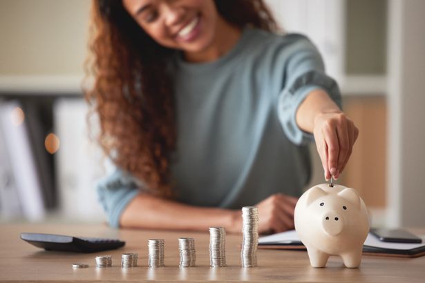 شابة أمريكية أمريكية أموال تضع العملات المعدنية في بنك الخنزير في المنزل. شخص مختلط شخص يحسب العملات المعدنية أثناء التخطيط المالي في غرفة المعيشة الخاصة بها. الادخار والاستثمار والتفكير في المستقبل