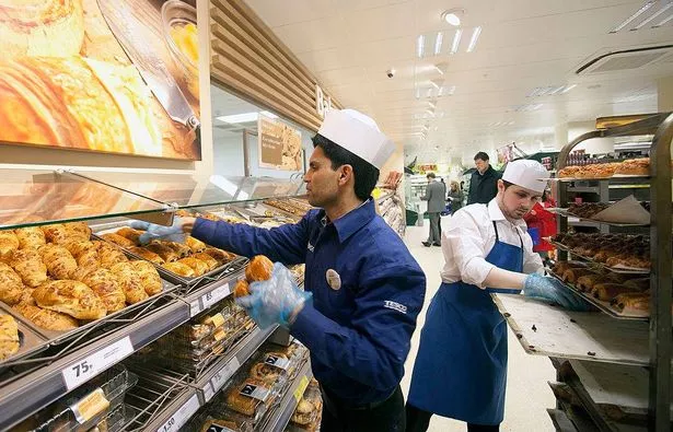 يقوم الموظفون بتجديد مخزونات الخبز في المخبز في متجر Tesco Metro