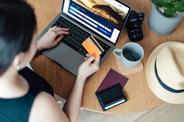 شابة تحجز تذكرة الطيران عبر الإنترنت باستخدام الكمبيوتر المحمول ، مما يؤدي إلى الدفع باستخدام بطاقة الائتمان ، والاستعداد للسفر. 