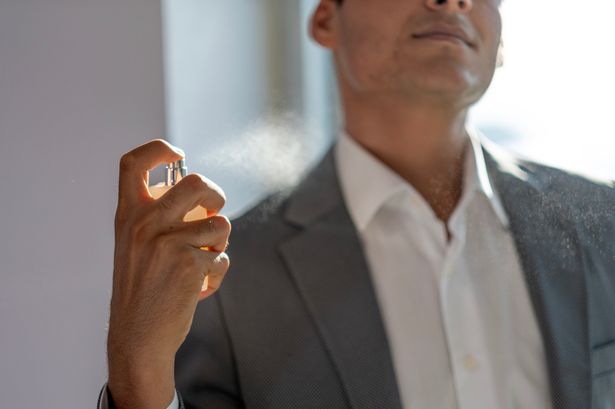 يرش الشاب العطر على جسده في طريقه إلى العمل في الصباح