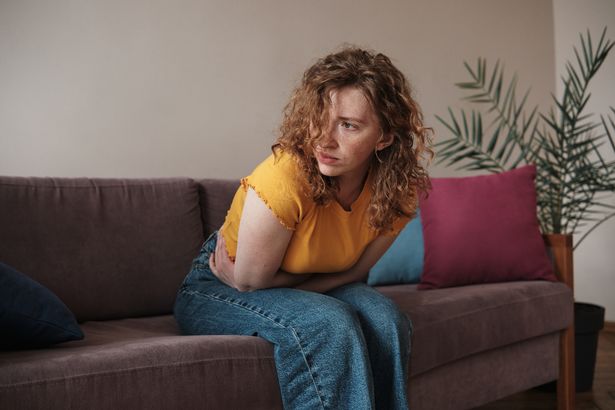 أعراض PMS. امرأة شابة تلمس البطن تعاني من آلام المعدة في المنزل