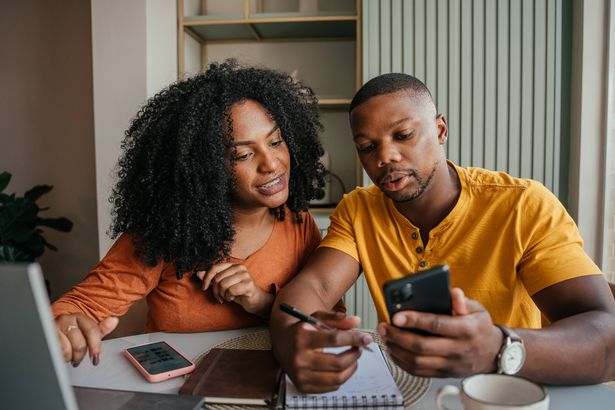 يجلس الزوجان على الطاولة مع عطلة حجز الكمبيوتر المحمول والهواتف