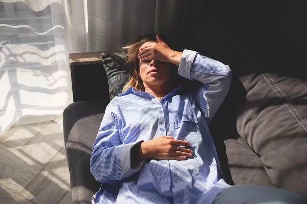 امرأة مستلقية على أريكة بيدها على جبينها ، مريض ، عام