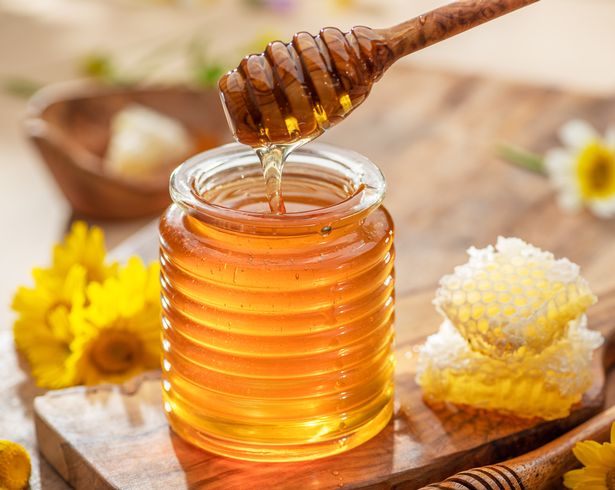 العسل العضوي الطبيعي في جرة زجاجية ، قحّب العسل ونقص العسل بالقرب من. خلفية الطعام الطبيعي.