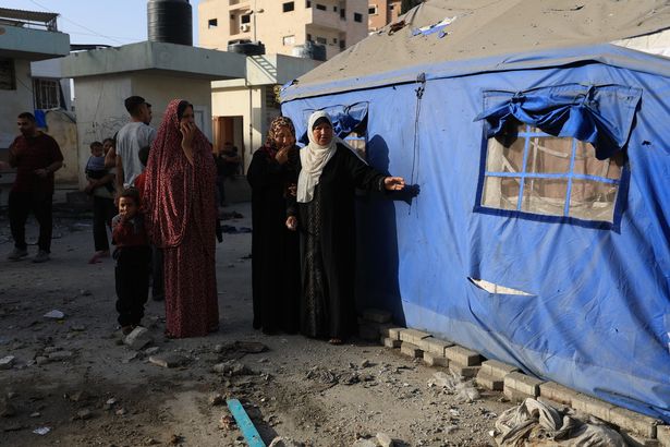 يبحث الفلسطينيون في المنطقة التي تلت غارة جوية إسرائيلية عند الفجر في المدرسة