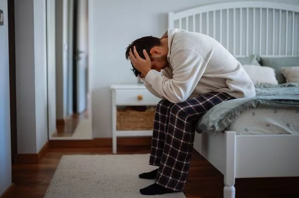 صورة مثيرة لبرنامج جذاب خائف ومكتئب في الأربعينيات من القرن الماضي على السرير في بيجامات يشعر بالقلق