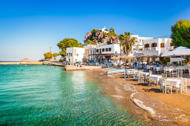 صورة أفقية مشرقة وملونة لمدينة سكالا. سماء زرقاء شريحة وشاطئ صغير بالقرب من ميناء باتموس ، اليونان.