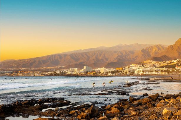Playa de las americas. متصفحي على الشاطئ في تينيريفي عند غروب الشمس