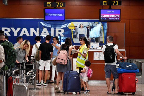 يتحدث أحد موظفي Ryanair إلى راكب في عدادات تسجيل الوصول مع العديد من الانتظار في المقدمة