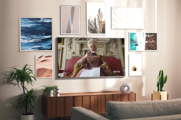 Samsung's The Frame Smart TV على جدار غرفة المعيشة محاطًا بالعمل الفني