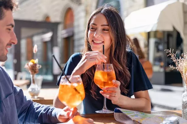 زوجان سعيدان في عطلة شرب Spritz على الطاولة في الهواء الطلق. فلورنسا ، إيطاليا