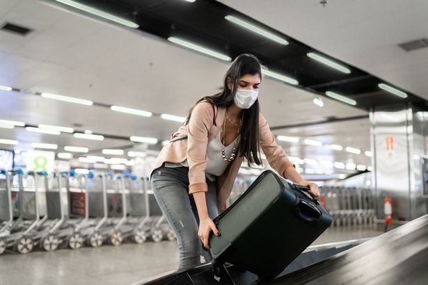 امرأة تلتقط حقيبة على حزام ناقل الأمتعة في المطار