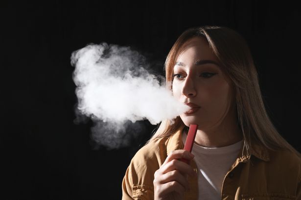 امرأة شابة تستخدم السجائر الإلكترونية على خلفية سوداء