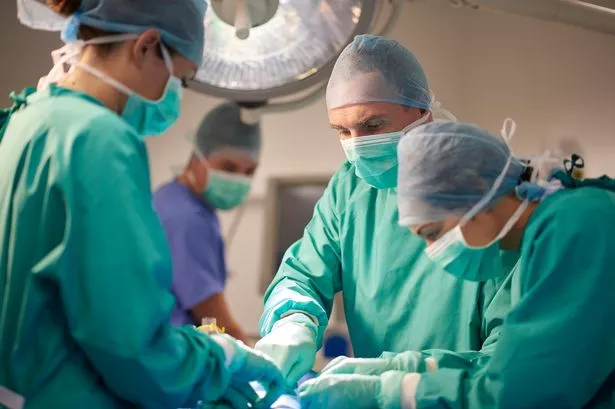 تقف ممرضة التشغيل فوق مريض على طاولة العمليات وتنظر إلى ما تفعله في العملية