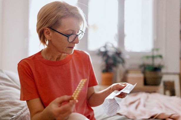 صورة عن قرب لامرأة تقرأ وصفة طبية في غرفة نومها خلال اليوم