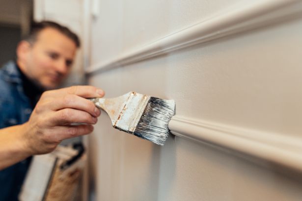 رجل يرسم لوحة جديدة ديي ديي Wainscot على الحائط في منزله.