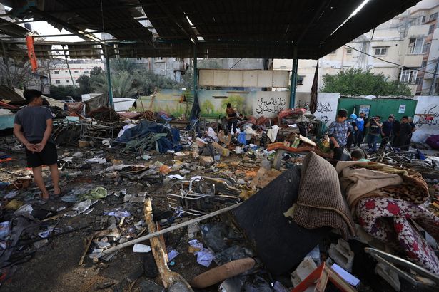 يبحث الفلسطينيون في المنطقة التي تلت غارة جوية إسرائيلية عند الفجر في المدرسة