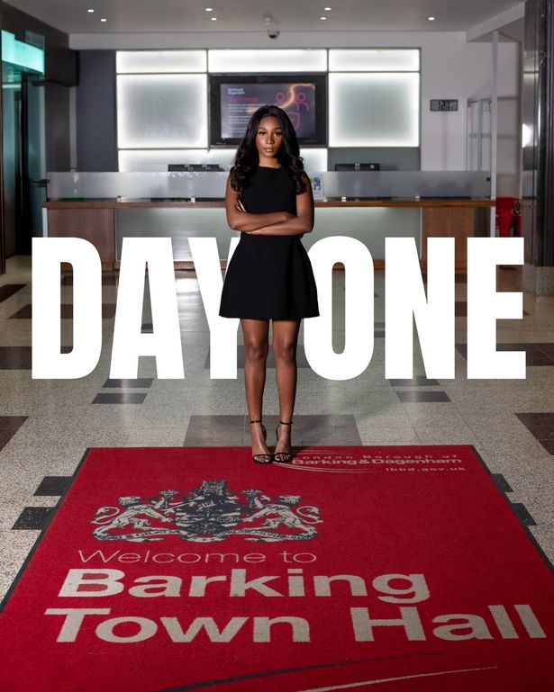 Cllr Princess Bright أمام Barking Town Hall مع عبارة "Day One" المكتوب خلفها ، مما يدل على أول يوم لها في المكتب