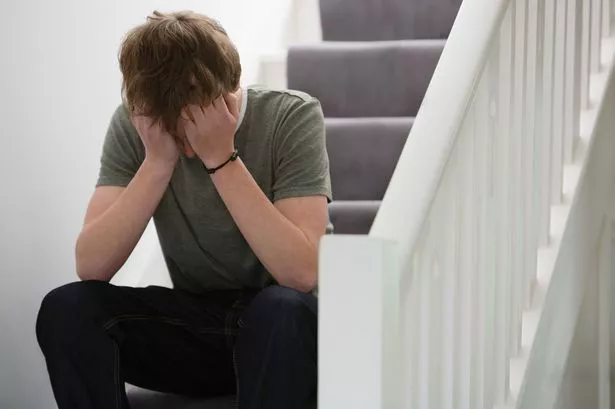 صبي مراهق مستاء يجلس على الدرج ورأسه في يديه