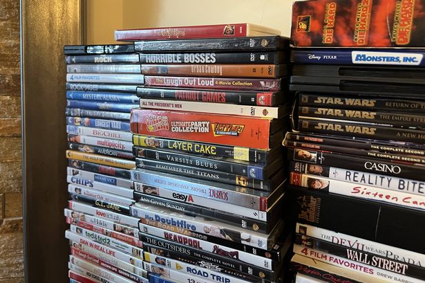 مجموعة متنوعة من أفلام أقراص DVD مكدسة في صفوف ، تتميز بمجموعة متنوعة من الأنواع والألقاب الشعبية. 