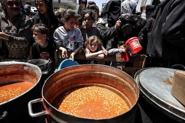 دير البلا ، غزة - 07 مايو: الفلسطينيون ، بمن فيهم الأطفال ، يجمعون لتلقي وجبات ساخنة وزعتها الجمعيات الخيرية في دير البلاه ، غزة ، في 07 مايو 2025. 