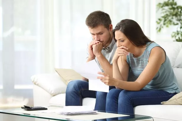 زوجان قلقان يقرأان إخطارًا مهمًا في رسالة جالسة على أريكة في غرفة المعيشة في المنزل