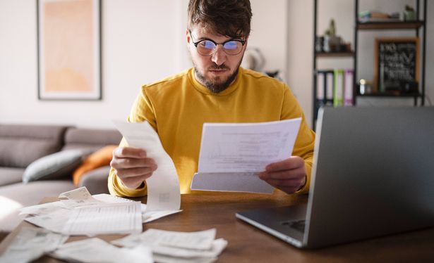 شاب في المنزل يحسب والتوافق على الفواتير المرتفعة والضرائب. مفهوم التضخم.