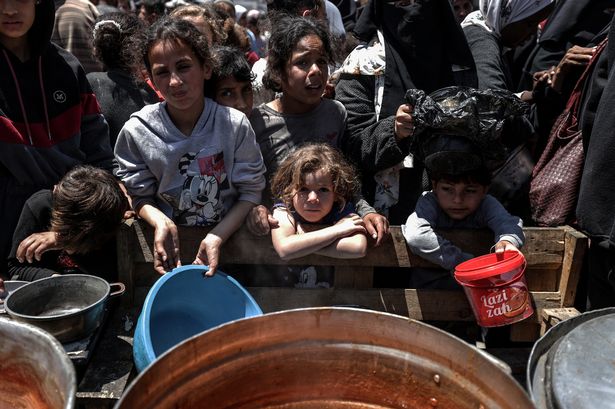 يتجمع الفلسطينيون لتلقي الوجبات الساخنة التي توزعتها الجمعيات الخيرية في دير البلا ، غزة ، في 7 مايو.