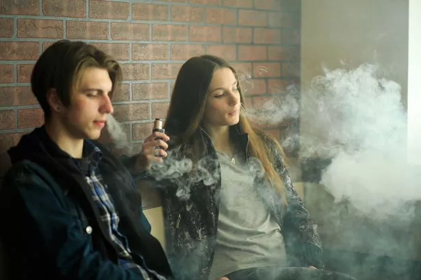 المراهقين vape. فتاة صغيرة لطيفة في النظارات الشمسية والشاب الوسيم يدخن السجائر الإلكترونية في بار vape. عادة سيئة ضارة بالصحة. نشاط vaping