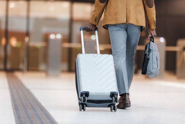 منظر خلفي لشخص يمشي في مطار يحمل حقيبة خلفه 