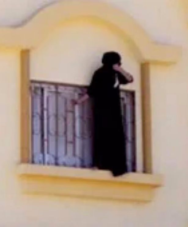 امرأة ترتدي أبيا تقف على حافة النافذة في ما يُعتقد أنه سجن سري