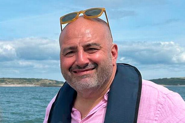وقفت Wynne Evans ، في قميص وردي وسروال شورت بني ، بجانب جوانا بيج ، في قمة زرقاء وسروال رمادي ، على متن قارب قبالة ساحل ويلز.