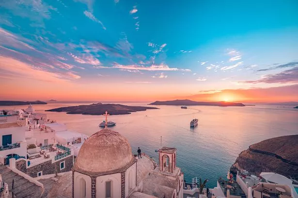 مشهد مسائي مذهل من Fira ، Infinity Pool Caldera View Santorini ، اليونان مع سفن الرحلات البحرية عند غروب الشمس. غائم غروب الشمس الدرامي ، مشهد صيفي رائع ، عطلة السفر ، عطلة. يلهم