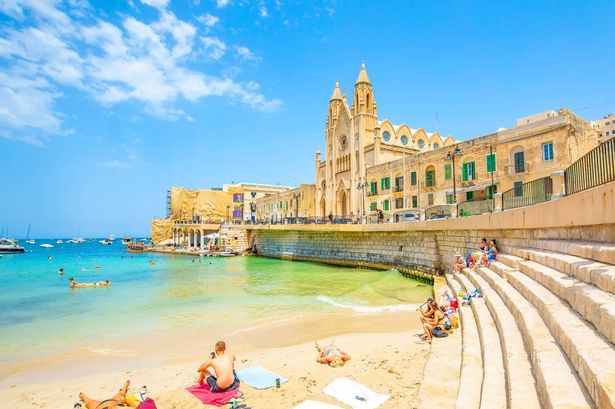 Balluta Bay Beach في مدينة سانت جوليان ، صورة السفر في مالطا. الشباب تقشعر لها الأبدان على الشاطئ