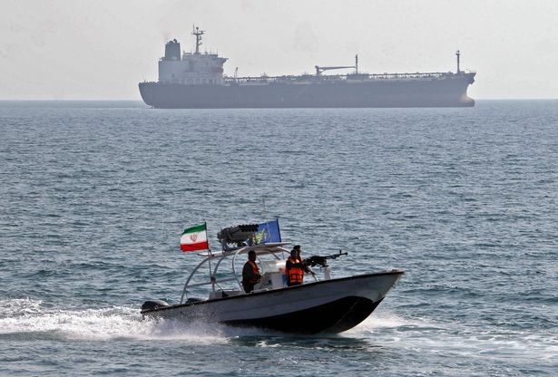 أعضاء فيلق الحرس الثوري الإسلامي الإيراني (IRGC) يركبون في قارب سريع أمام تانك النفط