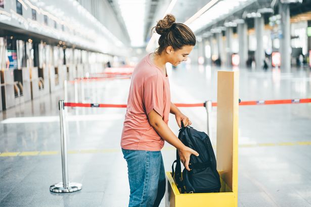 امرأة تتحقق من حجم أمتعتها المحمولة في المطار.