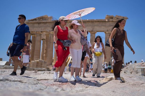 السياح الذين يعانون من مظلة المشي أمام معبد بارثينون القديم في هيل الأكروبوليس ، الخميس ، 26 يونيو 2025 كأول موجة حرارة في الصيف يضرب اليونان ، مع من المتوقع أن تحيط درجات الحرارة على مدى 40 درجة مئوية ، (104 فارينهايت) (AP Photo/Petros Giannakouris)
