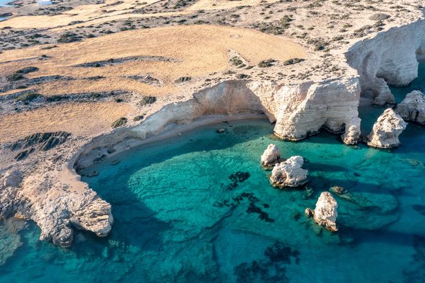 اليونان ، جزر سيكلاديس الصغيرة. Koufonisi المنعزل شاطئ الطائرات بدون طيار. المنحدرات الصخرية على مياه البحر فيروسية واضحة. يوم مشمس ، الوجهة الصيفية الهادئة
