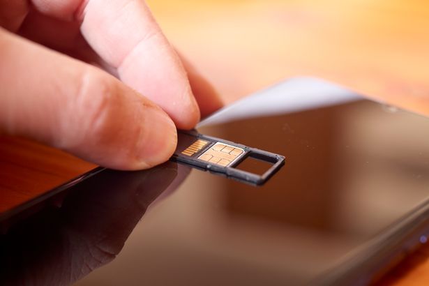 عرض عن قرب ليد الشخص الذي يحمل بطاقة SIM فوق هاتف ذكي ، يوضح المهمة المشتركة المتمثلة في تغيير أو إدخال بطاقة SIM