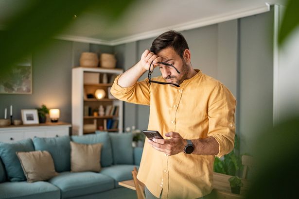 يشعر شاب بالاكتئاب والتفكير في الأخبار السيئة التي يقرأها عبر الإنترنت من خلال هاتفه الذكي