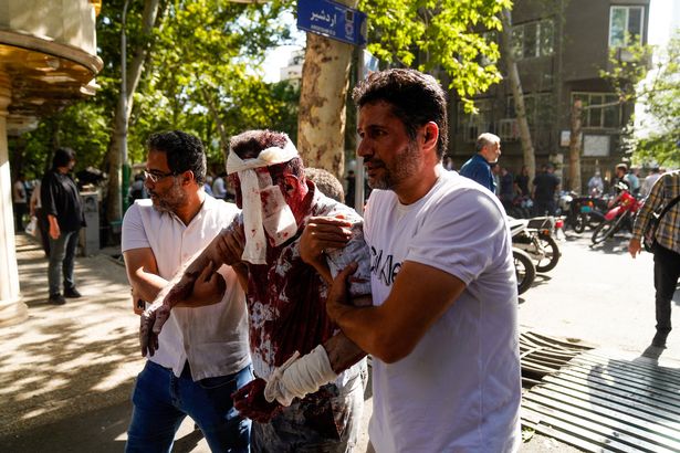 يهتم الإيرانيون برجل أصيب في ضربة إسرائيلية في شارع كيشافارز في وسط مدينة طهران 