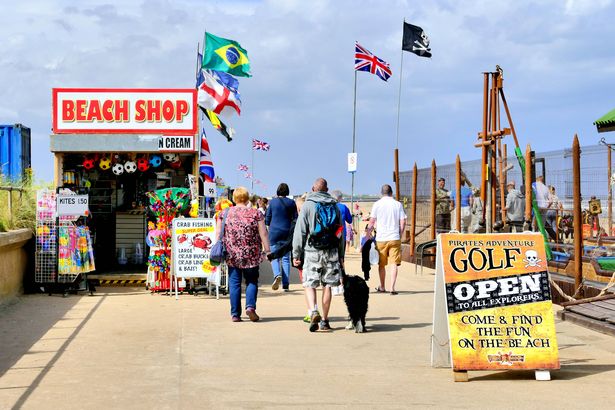 Ingoldmells ، Lincolnshire ، المملكة المتحدة. 09 أغسطس ، 2016. المصطافون يمشون في متجر شاطئ وجولف المغامرة.